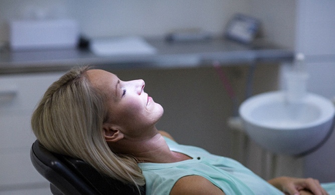 Woman sitting in dental chair with her eyes closed