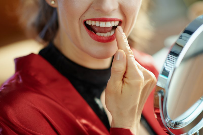 Patient smiling in the mirror at their dental implants